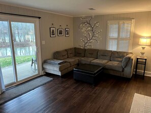 A living room with a sectional sofa, a coffee table, a side table with a lamp, and a decorative tree light.