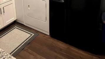 A kitchen with white cabinets, a black refrigerator, a stove, and a washing machine.