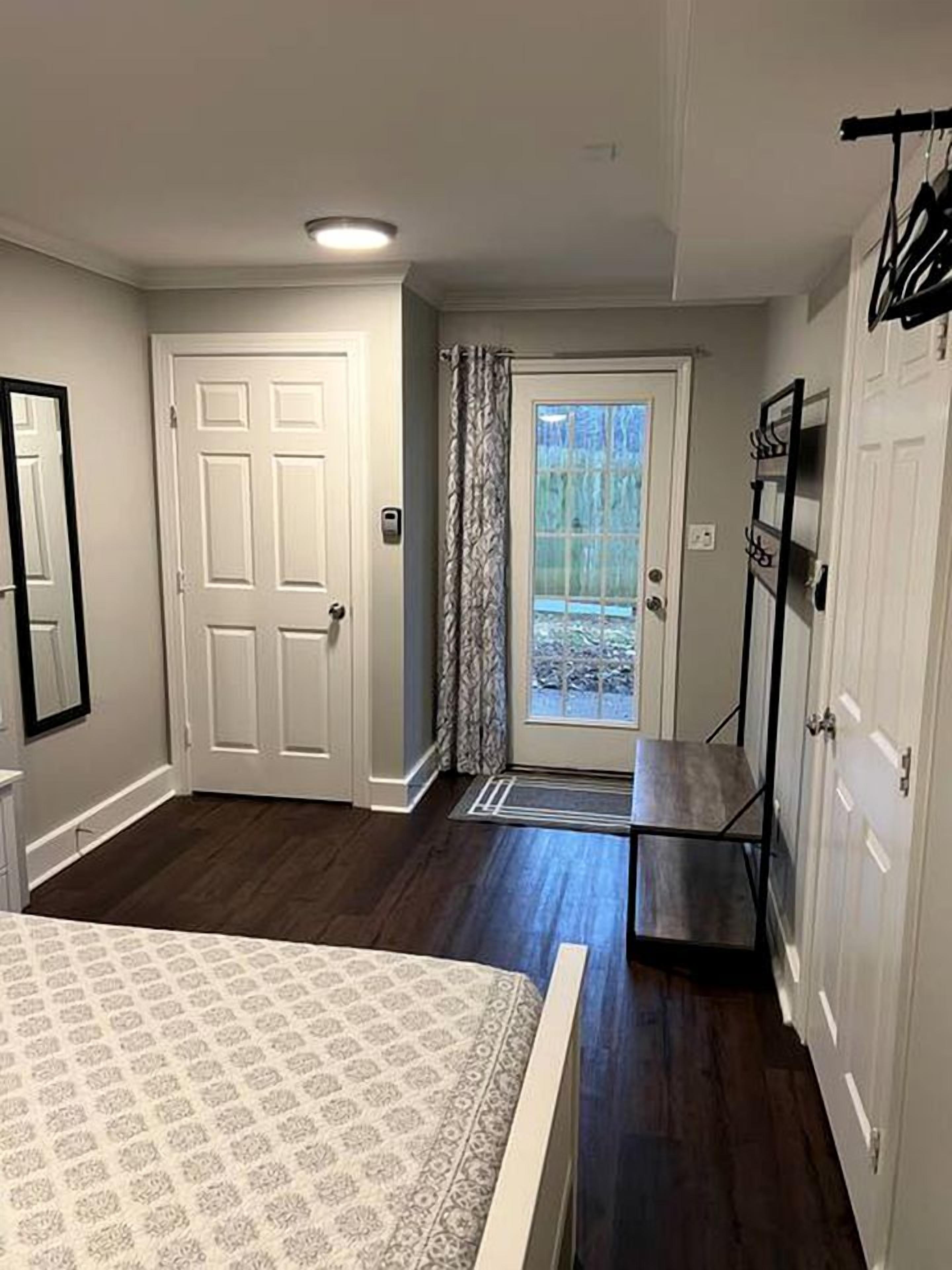 A bedroom with a bed, a door, a mirror, a wardrobe, and a view through a door.