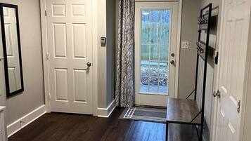 A bedroom with a bed, a door, a mirror, a wardrobe, and a view through a door.