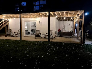 A covered outdoor area with seating and a staircase leading to an interior space.