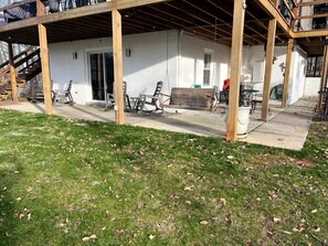 A covered patio area with outdoor furniture, a white building with a door, and a grassy lawn.