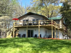 Une maison à deux étages avec un balcon, une véranda et une cour gazonnée.