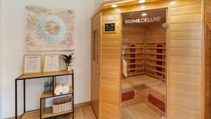 Una sauna de madera con un panel de control, un cartel que dice 'HOME DELUXE' y una obra de arte colgada en la pared.