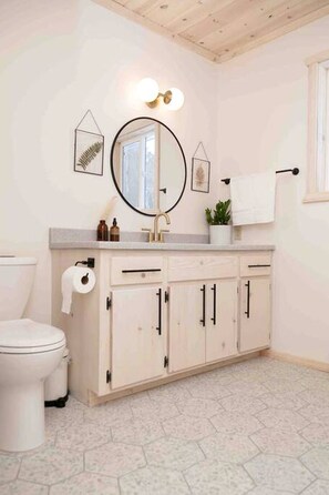 Un baño con inodoro, lavabo con espejo y un armario.