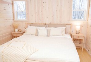A wooden cabin-style bedroom with a bed, two nightstands, and a window.