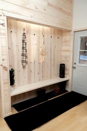 A wooden interior with a bench, a door, and a small shelf with a decorative item.