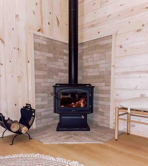 Una habitación con estufa de leña, una silla y una alfombra.