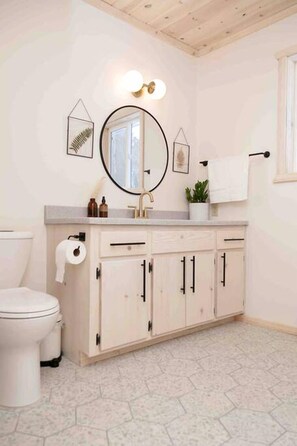 Ein Badezimmer mit Toilette, Waschbecken mit Spiegel und Schrank.