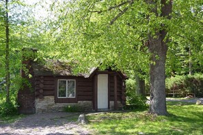Ein rustikales Holzhaus mit Steinunterbau, einer Holztür und einem Fenster.