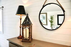 A wooden table with a lantern and a round mirror on the wall. - Sweet Tiny House Perfect for a Romantic Retreat in Alabama (Rogersville)