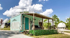 Un petit bâtiment d’un seul étage, avec une porte verte et un porche.