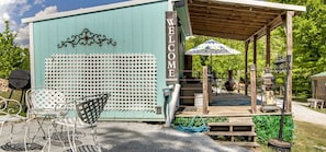 A rustic outdoor seating area with a wooden pergola, a welcome sign, and a lattice wall.