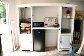 Eine kleine Küche mit Kühlschrank, Mikrowelle und einem Schild mit der Aufschrift 'Lake House Rules'.
