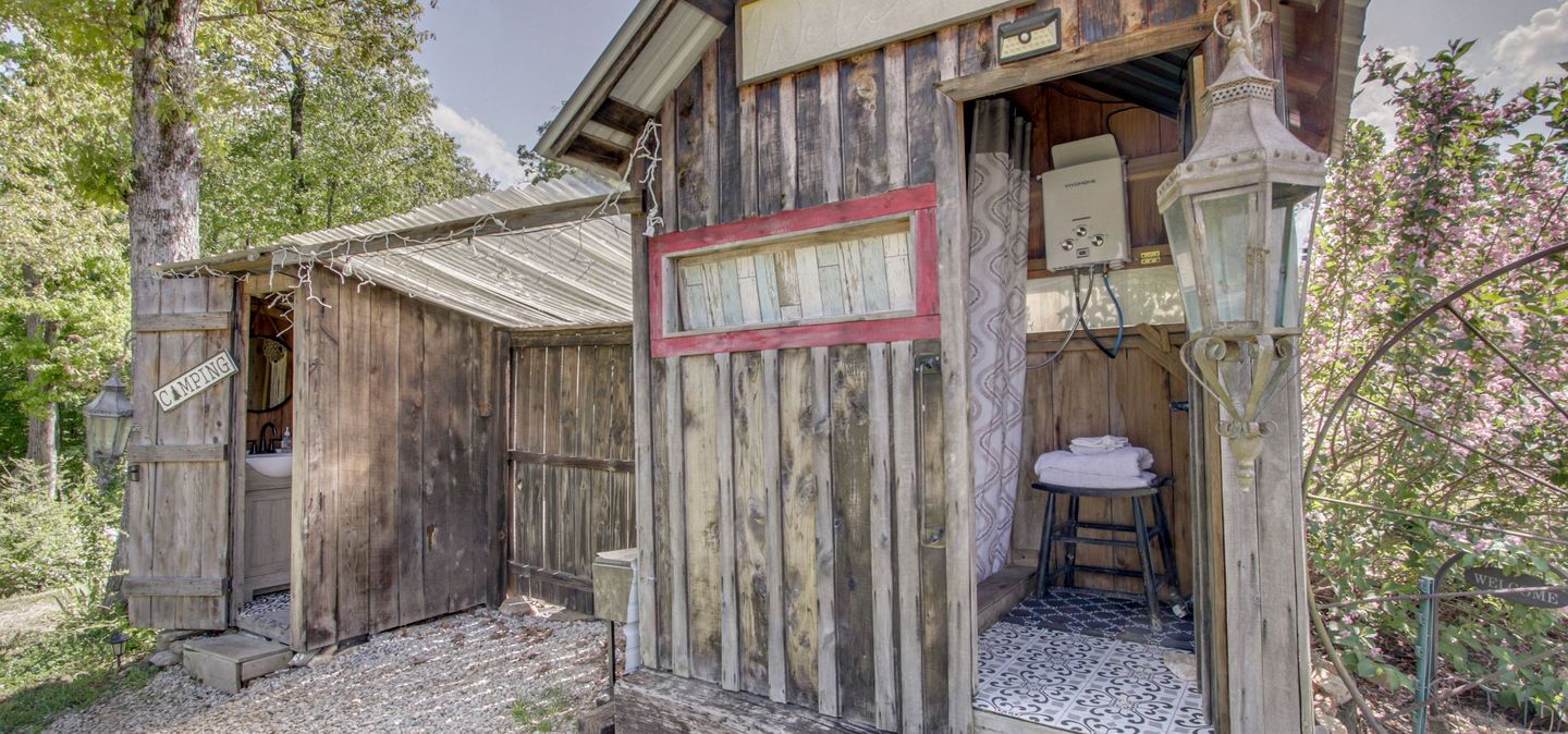 A rustic wooden cabin with a small bathroom, a welcome sign, and a power box.