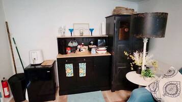 A room with a black cabinet, a small table with a lamp, and a blue sofa.