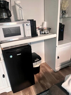 Una cuina compacta amb microones, cafetera i nevereta.