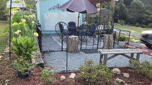 Een terras met tuinmeubilair, een pergola met zonwering en een tuin met planten en een houten bank.