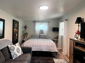 Ein Schlafzimmer mit einem Bett, einem Schlafsofa, einem Fernseher und einer Lampe.