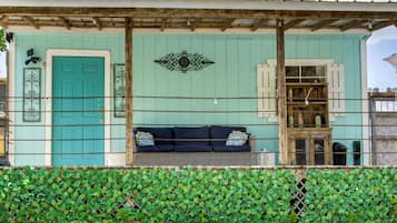 A building with a teal door, a black sofa with patterned cushions, and a decorative wall piece.