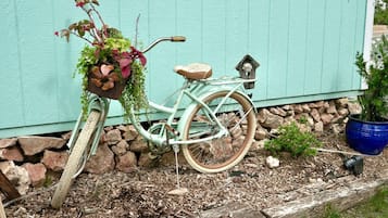 A vintage bicycle with a basket and a seat, parked against a teal wall.