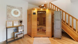 Un sauna en bois doté d’un panneau de commande, d’un escalier en bois et d’une affiche de yoga encadrée, posée sur une console.