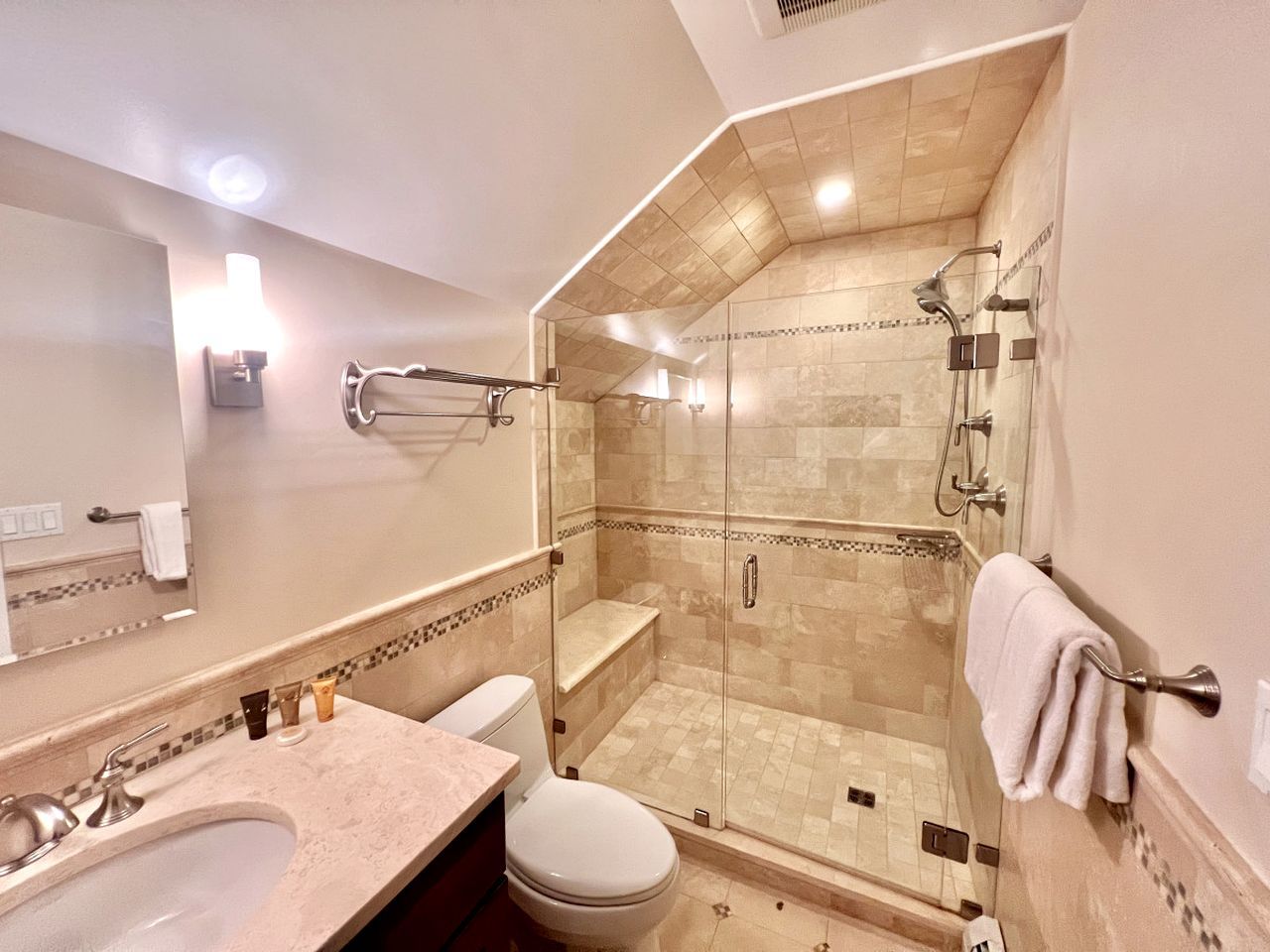 A modern bathroom with a glass-enclosed shower, a sink, and a toilet.