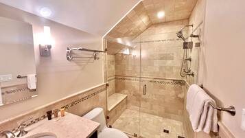 A modern bathroom with a glass-enclosed shower, a sink, and a toilet.