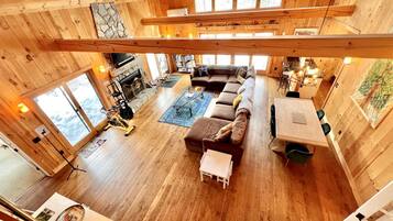 A spacious wooden cabin with a large living area, a fireplace, and a dining table.