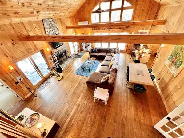 Una cabaña de madera espaciosa con una amplia sala de estar, chimenea y una mesa de comedor.