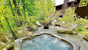 Ein Whirlpool, umgeben von Gartenmöbeln, einer Holztreppe und einem Gebäude mit einer Veranda.