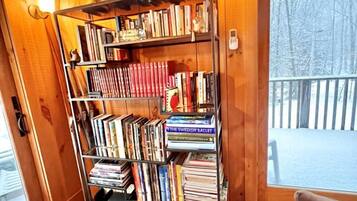 A wooden interior with a bookshelf, a door leading outside, and a view of a snowy landscape.