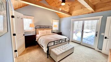 A bedroom with a bed, bench, and large windows.