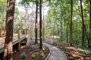 A forested area with a wooden deck and stone pathway.