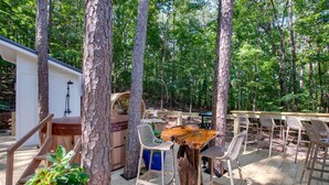 An outdoor deck with wooden chairs and tables, surrounded by trees. - Incredible Tented Cabin Nestled Amidst Trees in Scottsboro, Alabama (Scottsboro)