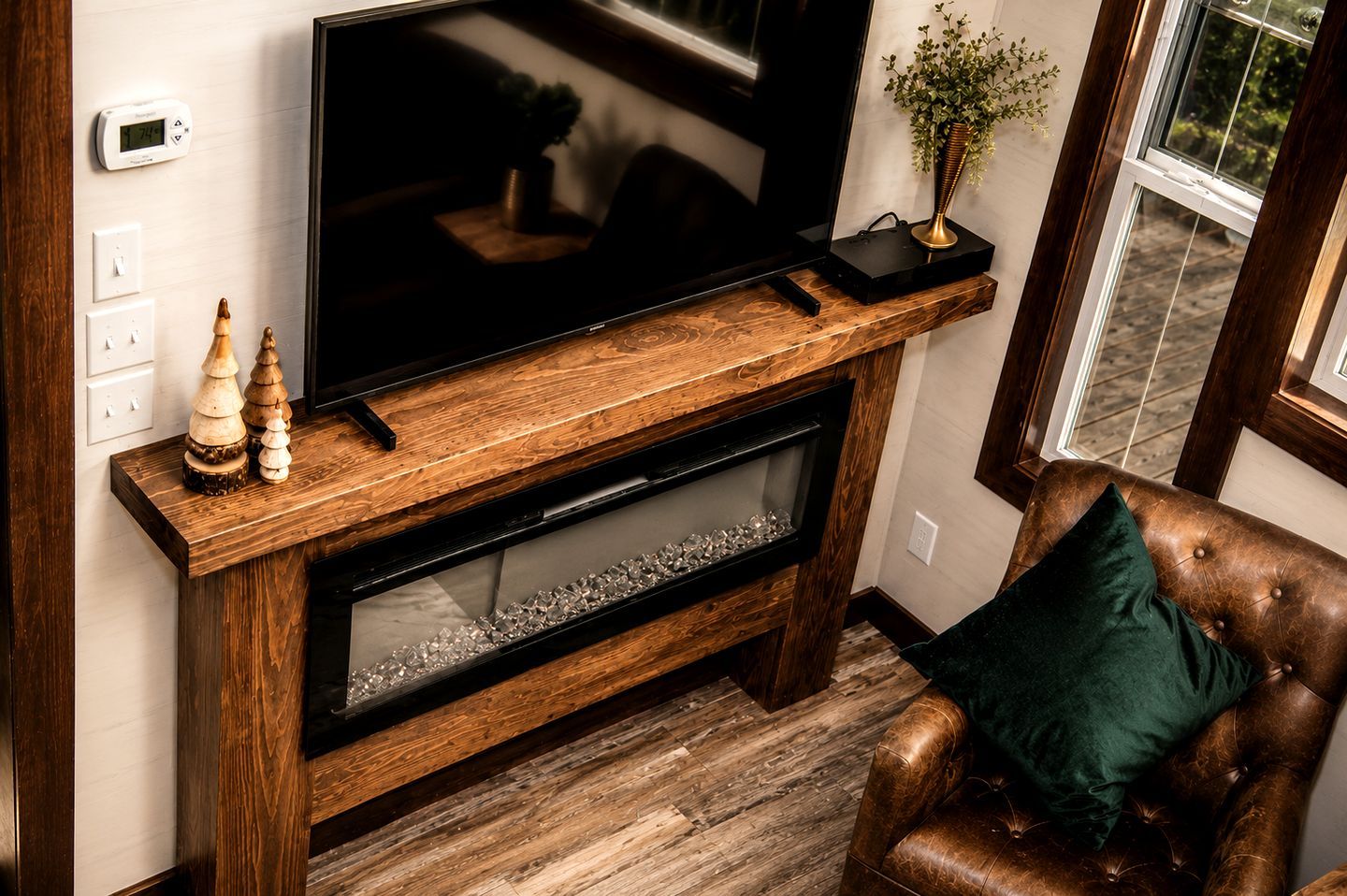 A wooden entertainment center with a flat-screen TV, decorative items, and a fireplace below.