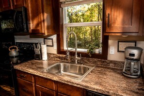 A kitchen with a granite countertop, stainless steel sink, and a coffee maker.