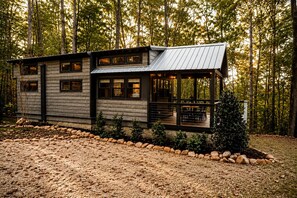 Une cabane dotée d’une terrasse, entourée d’arbres.