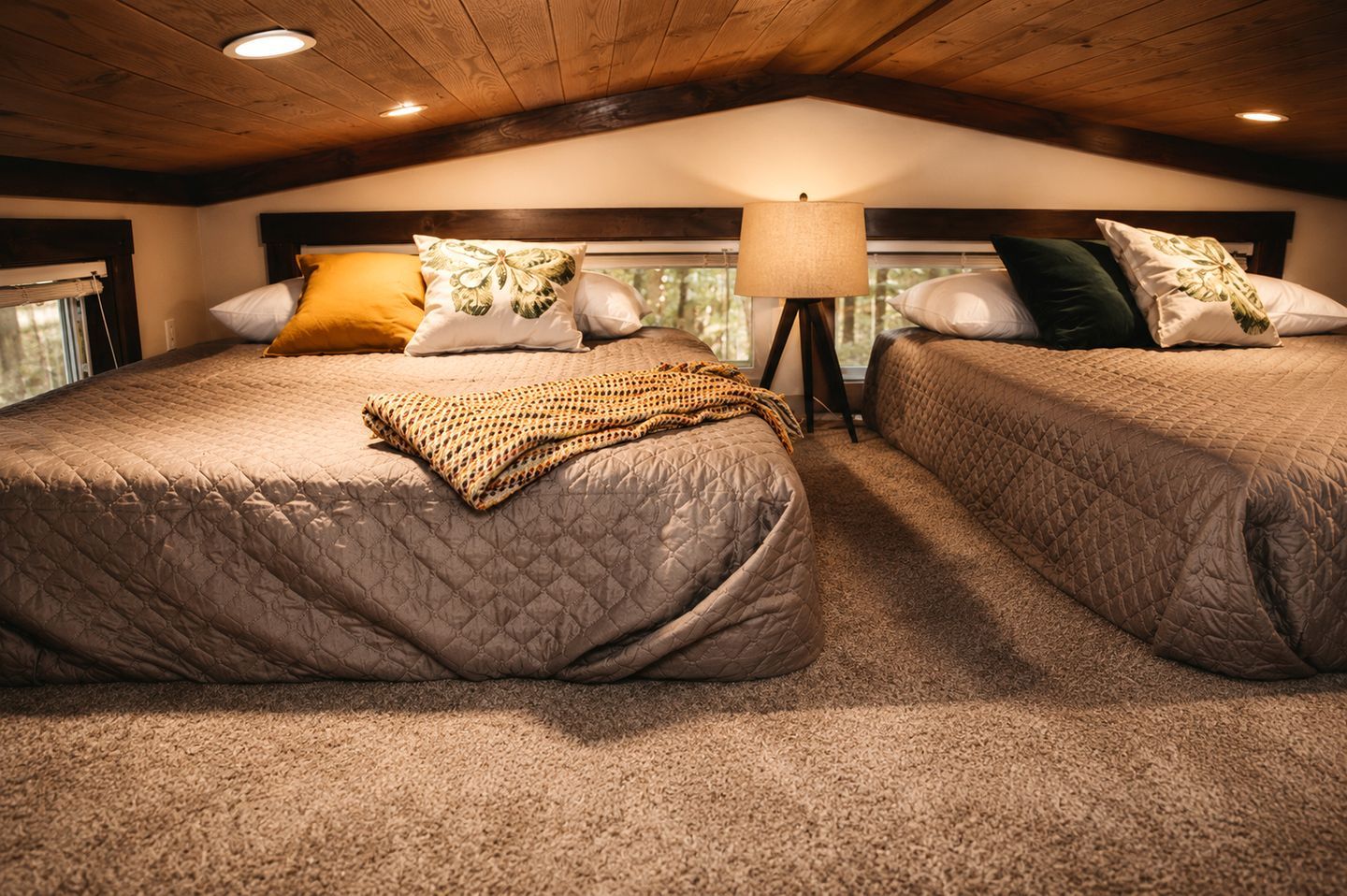 A cozy bedroom with two beds, a lamp, and a window.