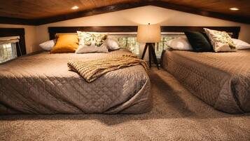 A cozy bedroom with two beds, a lamp, and a window.