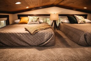 A cozy bedroom with two beds, a lamp, and a window.