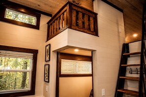 Un intérieur à plusieurs niveaux avec des poutres en bois, une mezzanine et un escalier.