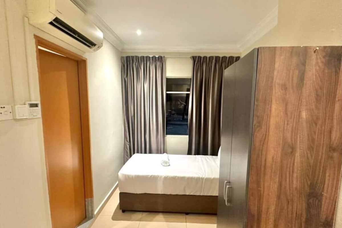Un dormitorio con cama, cortinas, armario y ventana.
