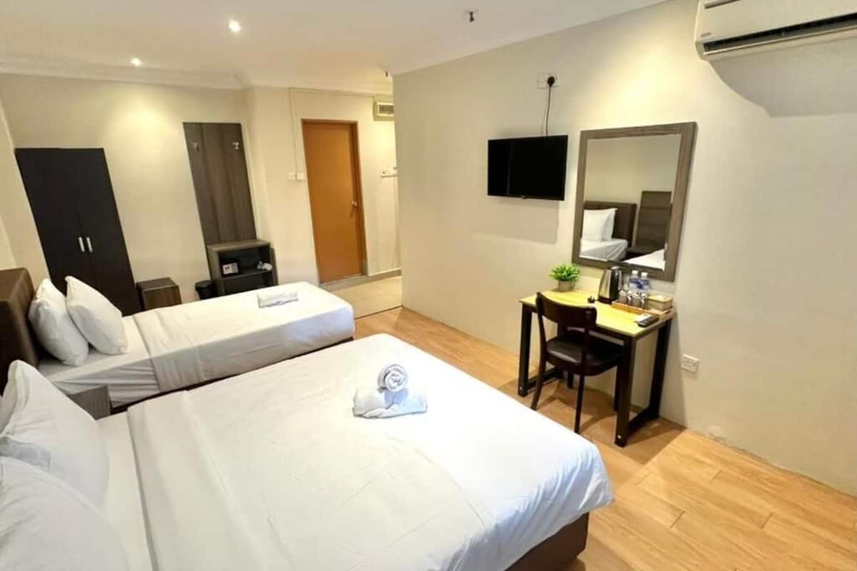 Habitación de hotel con dos camas, un escritorio, una silla, un televisor y un equipo de aire acondicionado.