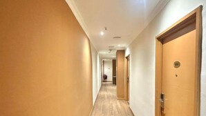 A hotel hallway with wooden flooring and doors on both sides. - Swing & Pillows at Bukit Bintang City (Kuala Lumpur)