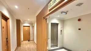 A hotel corridor with wooden flooring, a tiled area, and an elevator. - Swing & Pillows at Bukit Bintang City (Kuala Lumpur)