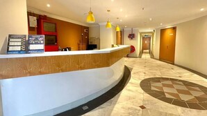 A hotel reception area with a curved reception desk, a red information board, and a tiled floor. - Swing & Pillows at Bukit Bintang City (Kuala Lumpur)