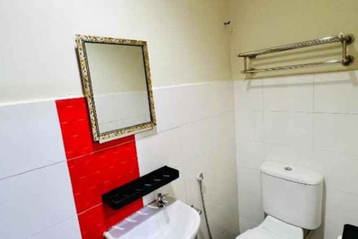 A bathroom with a white sink, a toilet, and a mirror with a decorative frame.