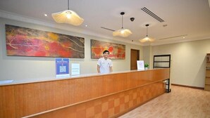A hotel reception area with a wooden reception desk, two large abstract paintings on the wall, and a modern ceiling design. - Swing & Pillows at Chinatown (Kuala Lumpur)