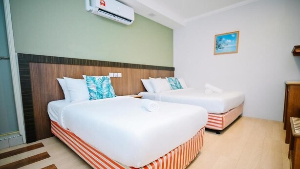 A hotel room with two beds, striped bedding, a wooden headboard, a small picture on the wall, and an air conditioning unit. - Swing & Pillows at Chinatown (Kuala Lumpur)